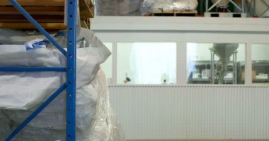 Genç bir beyaz kadın işçi fabrika stok kontrol yan görünüm. 4k