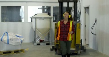 Forklift ve depo makinesinde çalışan beyaz kadın işçi önden görünümü. Bir palet mal raf 4 k depoda Paketli.