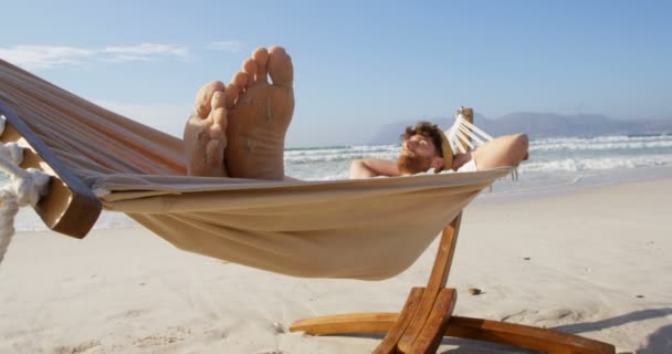 男がビーチでハンモックで寝ていた のハンモックでリラックスした男 — ストック動画