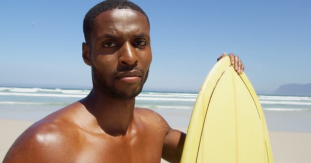 ビーチでサーフボードに立っている男性のサーファー のカメラを見て男性サーファー — ストック動画