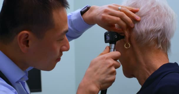 Joven Médico Asiático Examinando Paciente Mayor Con Otoscopio Clínica Joven — Vídeos de Stock