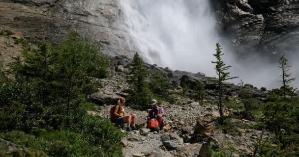 年轻的高加索徒步者夫妇的前面的看法与背包坐在森林中放松 他们在阳光下喝水 — 图库视频影像