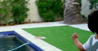 Yan görünüm siyah genç Aile evlerinin arka bahçesinde eğleniyor. Bankta oturan Anne ve oğlu 4 k arıyorsunuz