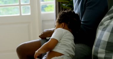 Yan küçük siyah oğlu babalar tur rahat bir ev içinde kanepede otururken uyanma, şirin görüntüleyin. Babası holding dizüstü 4k