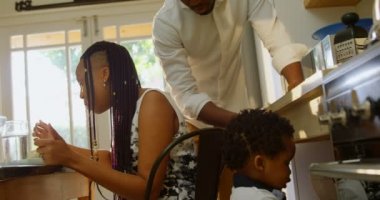Yan görünüm genç siyah baba ve oğul mutfak dolap içinde rahat bir ev arıyor. Anne yemek masası 4 k yemek yeme