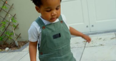 Şirin küçük siyah bebek evlerinin arka bahçesinde oynarken önden görünümü. O çalıştıran ve çakıl 4 k alarak