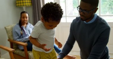 Genç siyah babası oğlunun yaşam rahat ev ile oynarken önden görünümü. 4 k kanepede oturan dizüstü bilgisayar ile anne