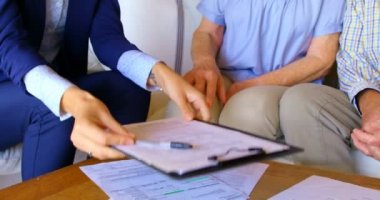 Emlakçı bölümünü eve rahat, üst düzey kadınla el sallayarak. 4 k evde kanepede rahatlatıcı