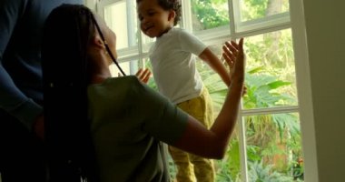 Siyah anne oğlu ile rahat bir ev pencere pervazına oynamaya yan görünüm. Oğlu anne 4 k doğru atlama