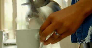 Siyah kadın dökerek sıcak suda kahve fincanı mutfakta yemek masasında close-up. Kahve Kupası 4 k gelen buhar