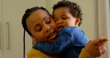 Sevimli küçük siyah bebek çocuk annesi rahat bir ev içinde kucaklayan önden görünümü. Anne ile bebek 4 k