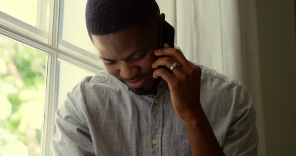 黑人青年在舒适的家中用手机说话的正面 他低下头 — 图库视频影像