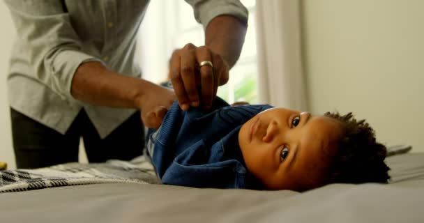 Середина Чорного Батька Допомагає Синові Змінювати Одяг Ліжку Комфортному Будинку — стокове відео