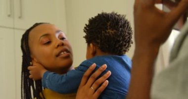 Genç siyah anne bebeğini rahat bir ev tutarak önden görünümü. Cep telefonu 4 k üzerinde konuşurken baba