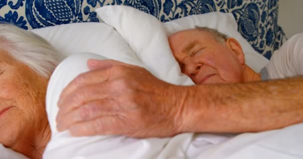快適な自宅の寝室のベッドで眠っている白人老夫婦のクローズ アップ のベッドの上の年配の女性に触れる年配の男性 — ストック動画