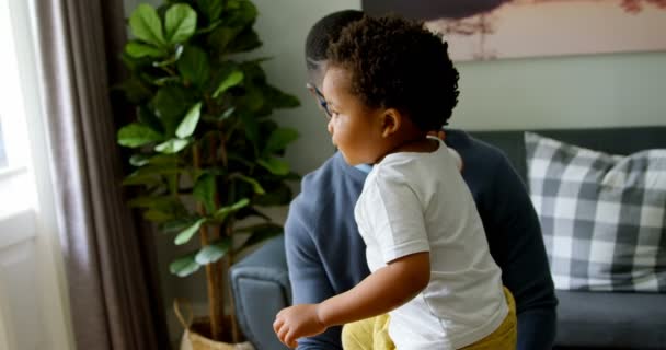 快適な家のリビングで息子と遊ぶ若い黒人の父のフロント ビュー 父は笑みを浮かべて の息子を見て — ストック動画