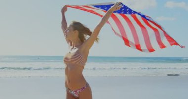 Bir Amerikan bayrağı sahilde tutan kadın. Amerikan bayrağı elinde 4 k çırpınan