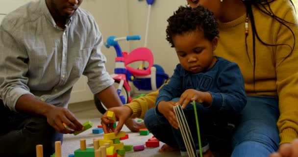 若い黒親と遊んで 快適な家の床に座って息子の側面図です 彼らはおもちゃや本 で遊んでいます — ストック動画