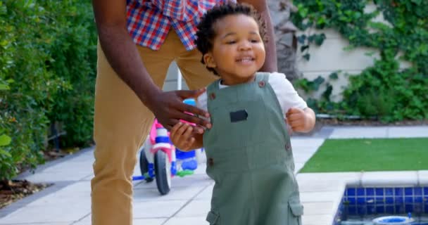 若い黒人の父と自宅の裏庭で遊ぶ幼い息子の正面 息子の笑顔と をジャンプ — ストック動画
