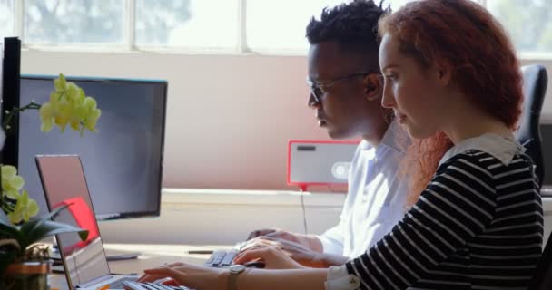 近代的なオフィスにラップトップとデスクトップ に取り組んでいる若い混血事業チームの側面図です 彼らは の机に座って — ストック動画