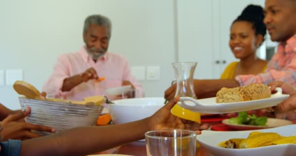 Boční pohled na multi generace černé rodiny s jídlem na jídelní stůl v pohodlí domova. Chlapec s jídlem deska 4k