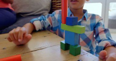 Önden Görünüm'de rahat bir ev tabloda oyuncaklarla oynarken küçük karma yarış çocuk. Blok 4 k ile bina yapıyor