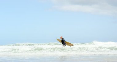 Eski beyaz komuta sizde surfboard ile plajda çalışan yan görünüm. Güzel gök ve 4k planda sakin deniz