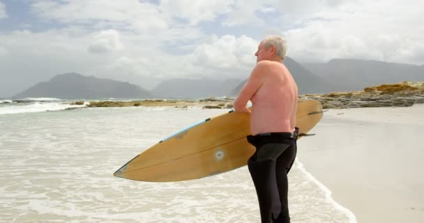 Vista Lateral Del Viejo Hombre Caucásico Llevando Tabla Surf Cabeza — Vídeos de Stock