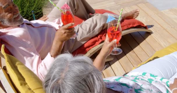 黑色高级夫妇在他们家后院的泳池甲板椅子上放松的高角度视野 他们在敬酒 喝着鸡尾酒4K — 图库视频影像