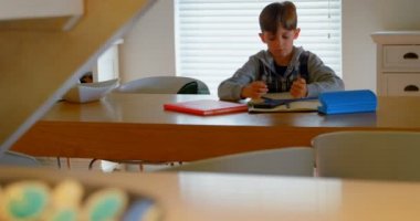 Önden Görünüm beyaz çocuğun yemek masada rahat bir ev ödevini yapıyor. Defter 4 k yazıyor