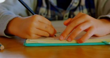 Önden Görünüm beyaz çocuğun yemek masada rahat bir ev ödevini yapıyor. O kitabı 4 k eskiz çiziyor