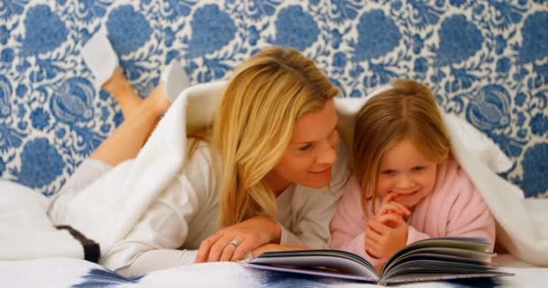 在年轻的高加索母亲和女儿的正面看着相册在家里的床上 他们在毯子4K — 图库视频影像