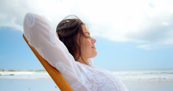 年轻的高加索妇女在海滩上的双目人头部放松双手的侧视图 年轻的高加索妇女坐在闭着眼睛4K — 图库视频影像
