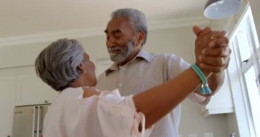 Üst düzey siyah çift birlikte rahat evde mutfakta dans yan görünüm. Gülümseyen ve el ele 4 k