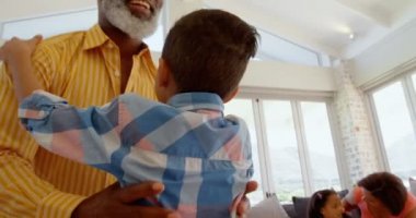 Önden Görünümü kucaklayan olgun siyah baba oğul rahat ev oturma odasında sakladı. O gülümseyen ve 4 k gözaltında