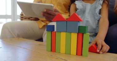 Kanepede oturan ve rahat bir ev yapı taşları ile oynayan kız orta bölümü. 4 k dijital tablet üzerinde çalışan baba