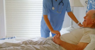 Yatakta rahat bir ev içinde Komuta sizde elini tutarak genç Kafkas kadın doktor önden görünümü. O teselli ve 4 k onunla konuşurken