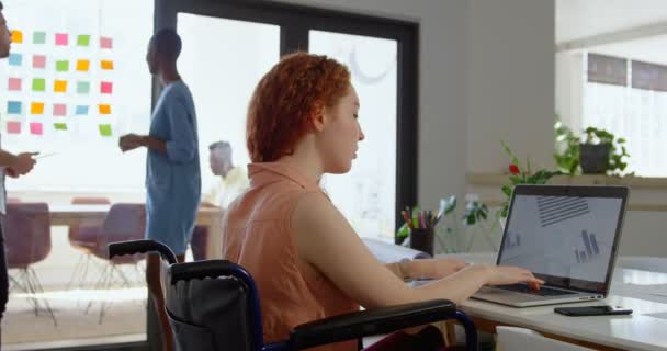 在现代办公室里从事笔记本电脑工作的年轻高加索女商人的侧视图 混血同事相互互动4K — 图库视频影像