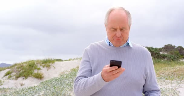 Framifrån Kaukasiska Senior Gubbe Med Mobiltelefon Stranden Han Kontrollerar Sin — Stockvideo