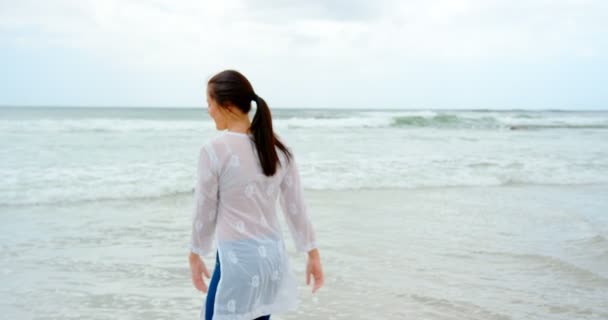 在阳光明媚的日子里 站在海滩上的年轻高加索妇女的正面景色 她面带微笑 玩得很开心 — 图库视频影像