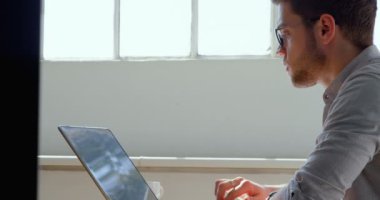 Laptop modern bir ofiste çalışan genç beyaz işadamı yan görünüm. 4 k masada oturuyor