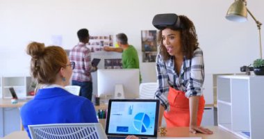 Masa başında birbirleriyle etkileşim oldukça karışık ırk kadın yöneticilerin ön görünümü. Arka planda çalışan çok ırklı iş arkadaşları 