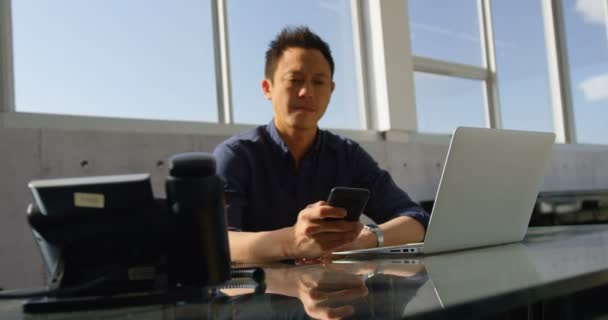 若いアジア ビジネス男性エグゼクティブ オフィス デスクで携帯電話を使用しての正面 彼はテキスト メッセージ本文 — ストック動画