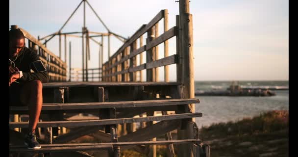 Rear View Young African American Male Jogger Sitting Pier Using — Stock Video