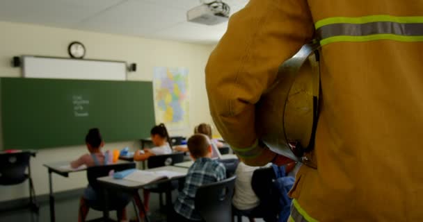 Vista Trasera Del Bombero Masculino Entrando Aula Escuela Los Niños — Vídeo de stock