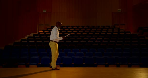 空の講堂でスピーチを練習して上級のアフリカ系アメリカ人実業家の側面図です 彼は歩いていると を身振りで示すこと — ストック動画