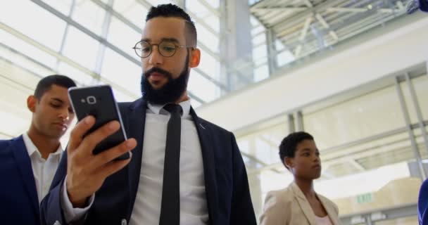 ビジネスセミナー4Kで携帯電話を使用しながら キューに立っている混合人種のビジネスマンの低角度ビュー — ストック動画