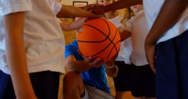 Düşük görüş açısı genç beyaz erkek basketbol takımı koçu ve el yığın basketbol sahası içinde şekillendirme schoolkids, basketbol 4 k tutuyorlar