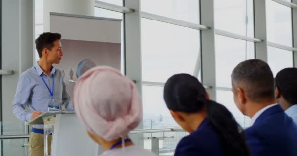 ビジネスセミナーで表彰台に立つアジア人男性スピーカーの側面図 — ストック動画