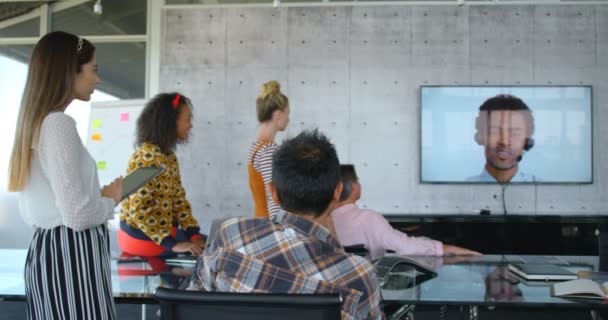 の背景で画面を見てビジネス人々 に対して近代的なオフィスでビデオ会議を行う多様な経営者の背面図 — ストック動画